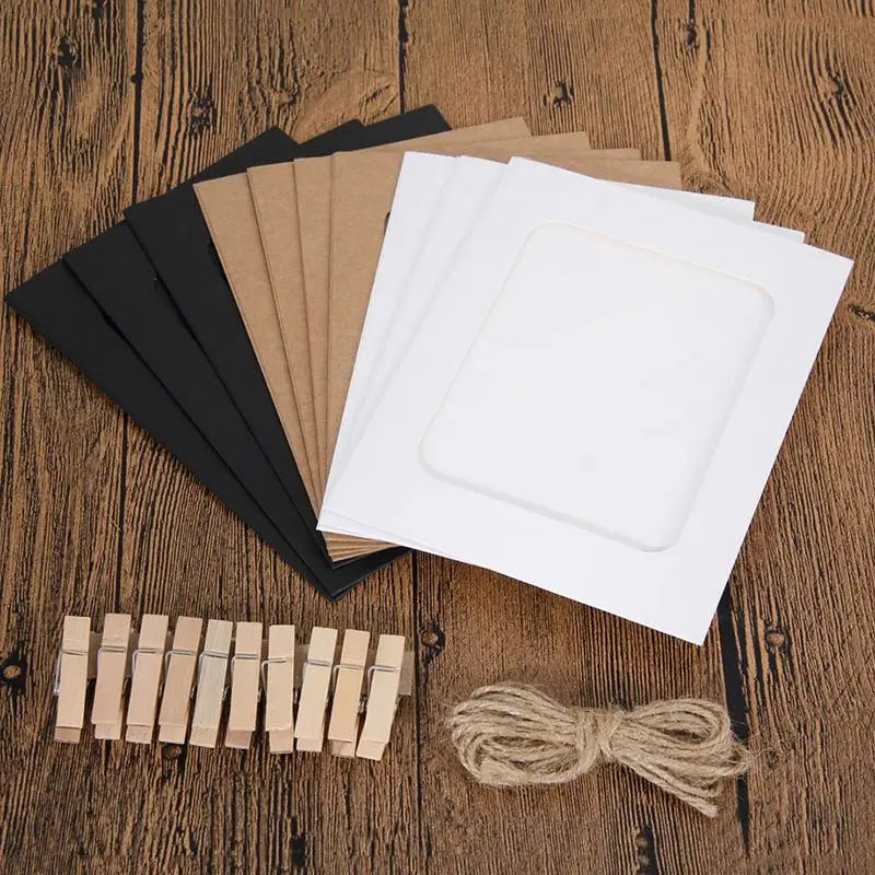 Un juego de marcos de fotos blancos vacíos, soporte de cartón y clips de madera con cuerda natural sobre una superficie de ma