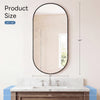 A round oval mirror with a black metal frame hanging above a marble vanity countertop.