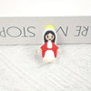 A small resin statue of the Virgin Mary with a yellow halo and red garment displayed on a white surface.