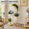 A white metal 4-tier plant stand with decorative scrollwork, showing its dimensions and use in a bright room.