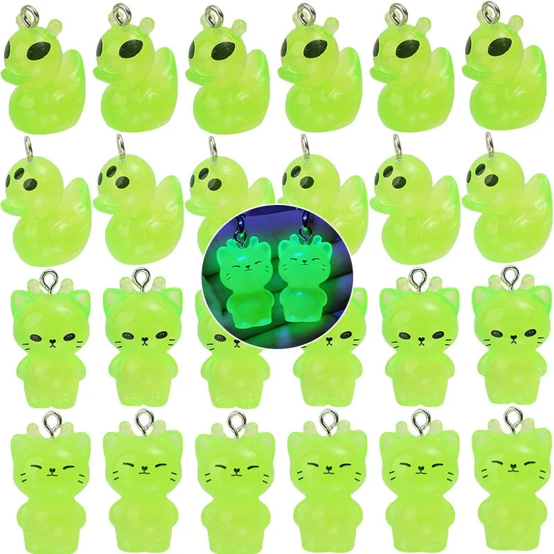 A collection of glow-in-the-dark cartoon alien kitty duck resin charms in various shades of neon green.