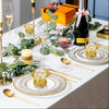 A table setting featuring gold crown candy boxes, silver plates, and glassware for a formal event.