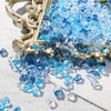 A close-up of crushed blue acrylic pebbles displayed in a gold-toned decorative frame on a white surface.