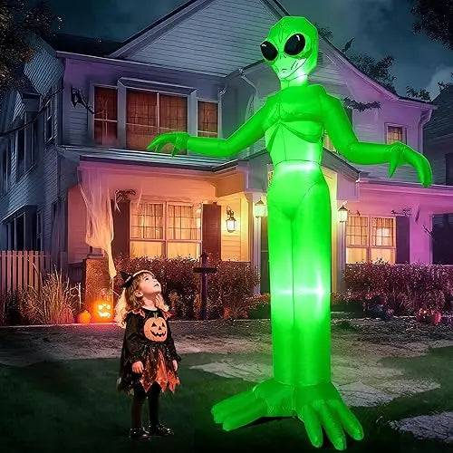 A 9ft tall green alien inflatable decoration with LED lights standing in a suburban yard at night.