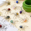 A collection of handcrafted crystal spider figurines in various colors and sizes displayed on a light background.