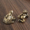 Antique brass frog sculpture decor resting on a dark wooden surface.