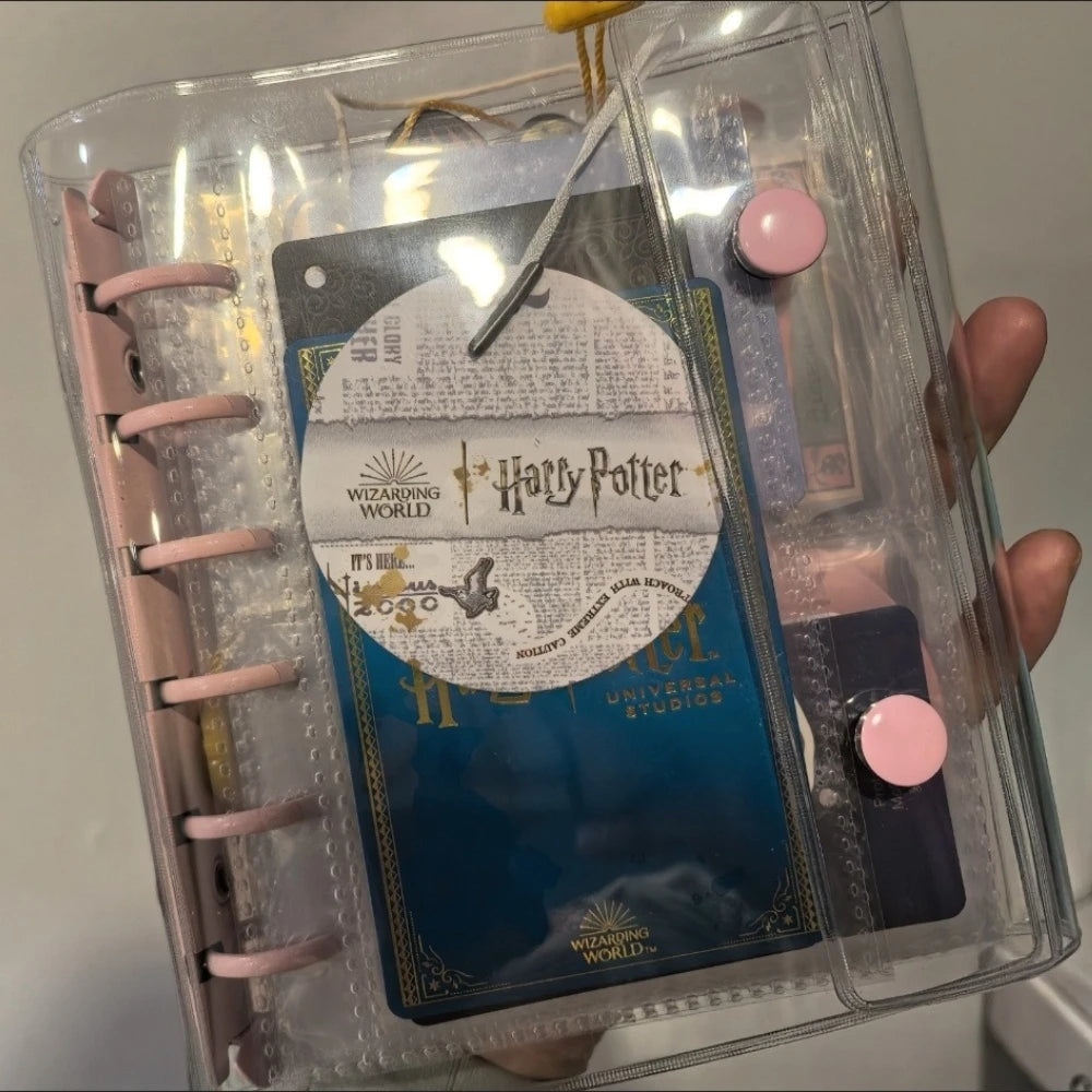 A clear binder holds a pink macaron binder with a Harry Potter themed card and other collectibles.