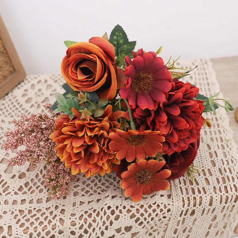 A bouquet of silk autumn roses and hydrangeas in shades of orange, rust, and deep red.