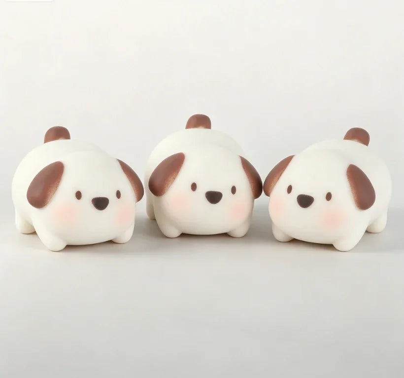 Three white pig mochi squishy toys with brown ears resting on a white surface.
