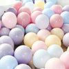 A close-up of assorted pastel macaron balloons in various shades including pink, purple, yellow, and blue.