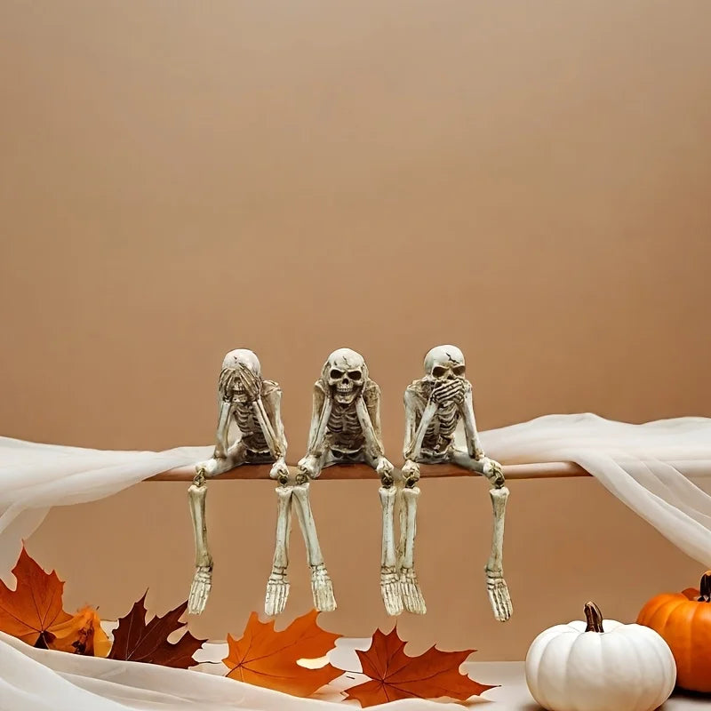 A set of realistic Halloween skeleton resin statues displayed on a wooden surface with white fabric and autumn leaves.