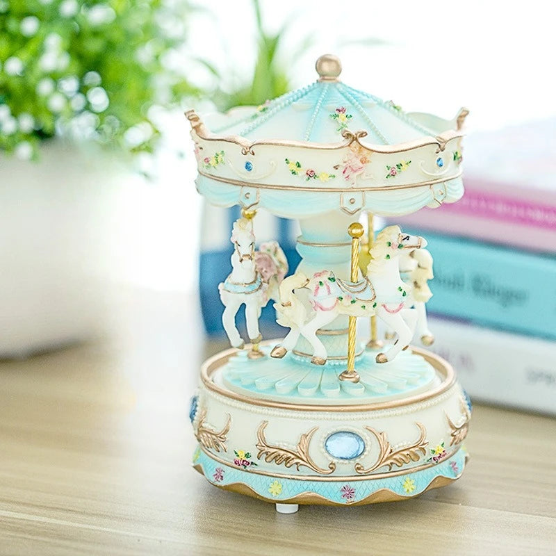 A delicate light blue resin carousel music box with a crown and horses on a wooden surface.