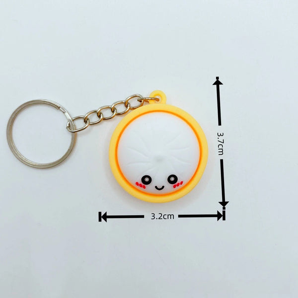 A yellow circular charm shaped like a smiling food item is attached to a silver chain.