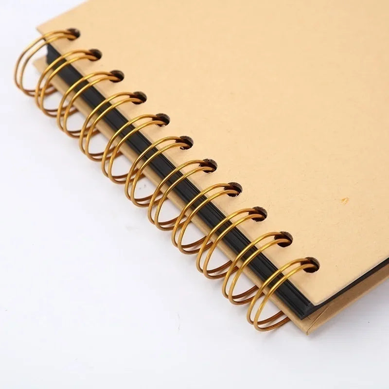 A close-up view of a tan notebook with black spiral binding and gold-colored metal rings.