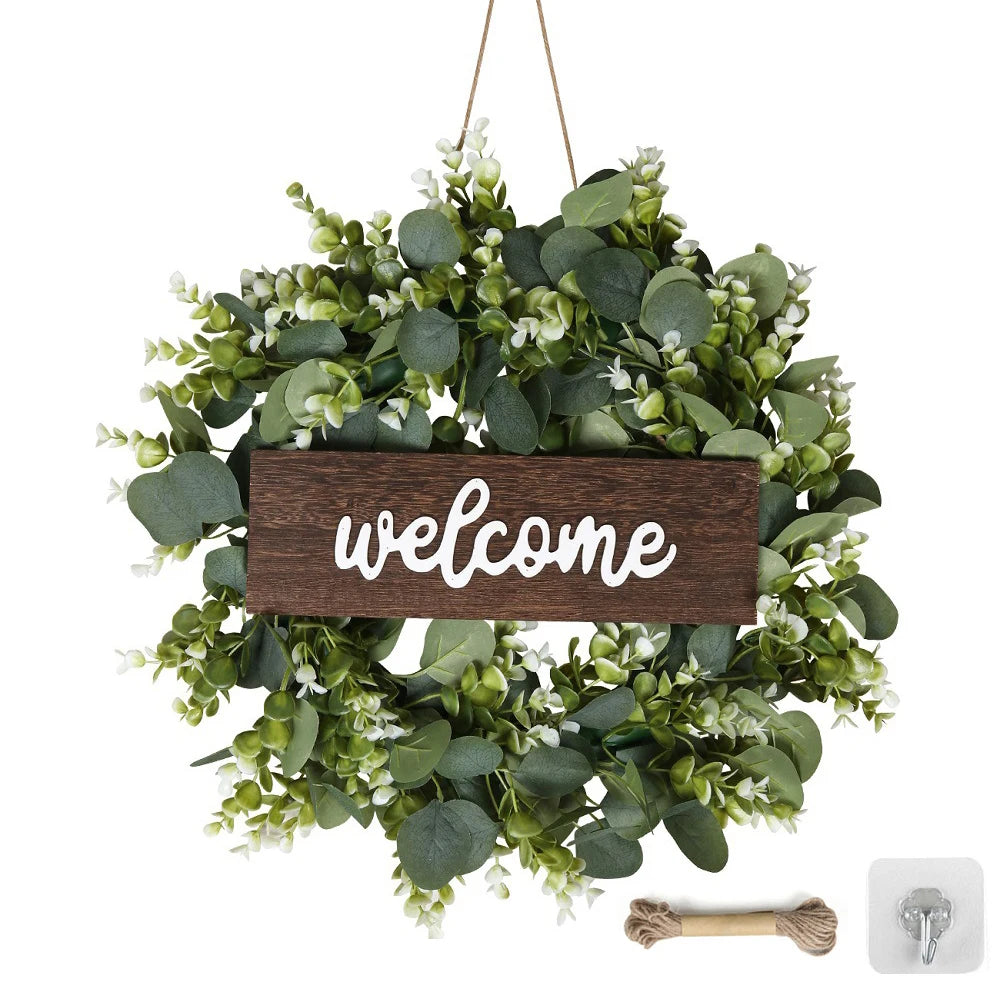 Artificial eucalyptus wreath with green leaves and white flowers featuring a wooden welcome sign