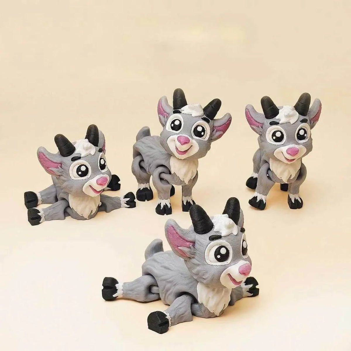 Three 3D printed goat figurines in gray and white are displayed against a light background.