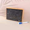 A wooden savings box with a grid of numbers is shown next to a blue pen.