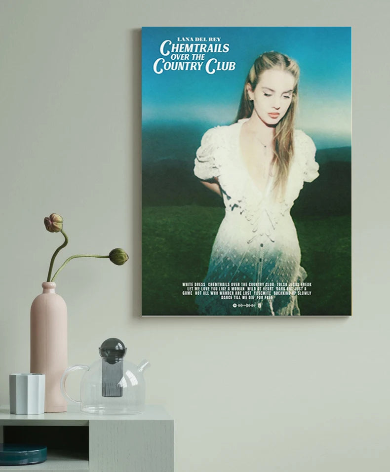 A painting titled Chemtrails Over the Country Club featuring a woman with long hair in a white dress against a green landscap