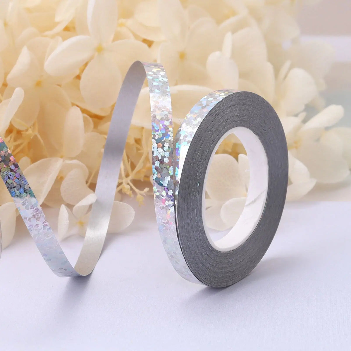 Roll of iridescent silver and holographic satin balloon ribbon unwinding