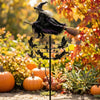 A whimsical witch wind rotor garden decor featuring a witch figure with a pointed hat and feathered wings, set against an aut