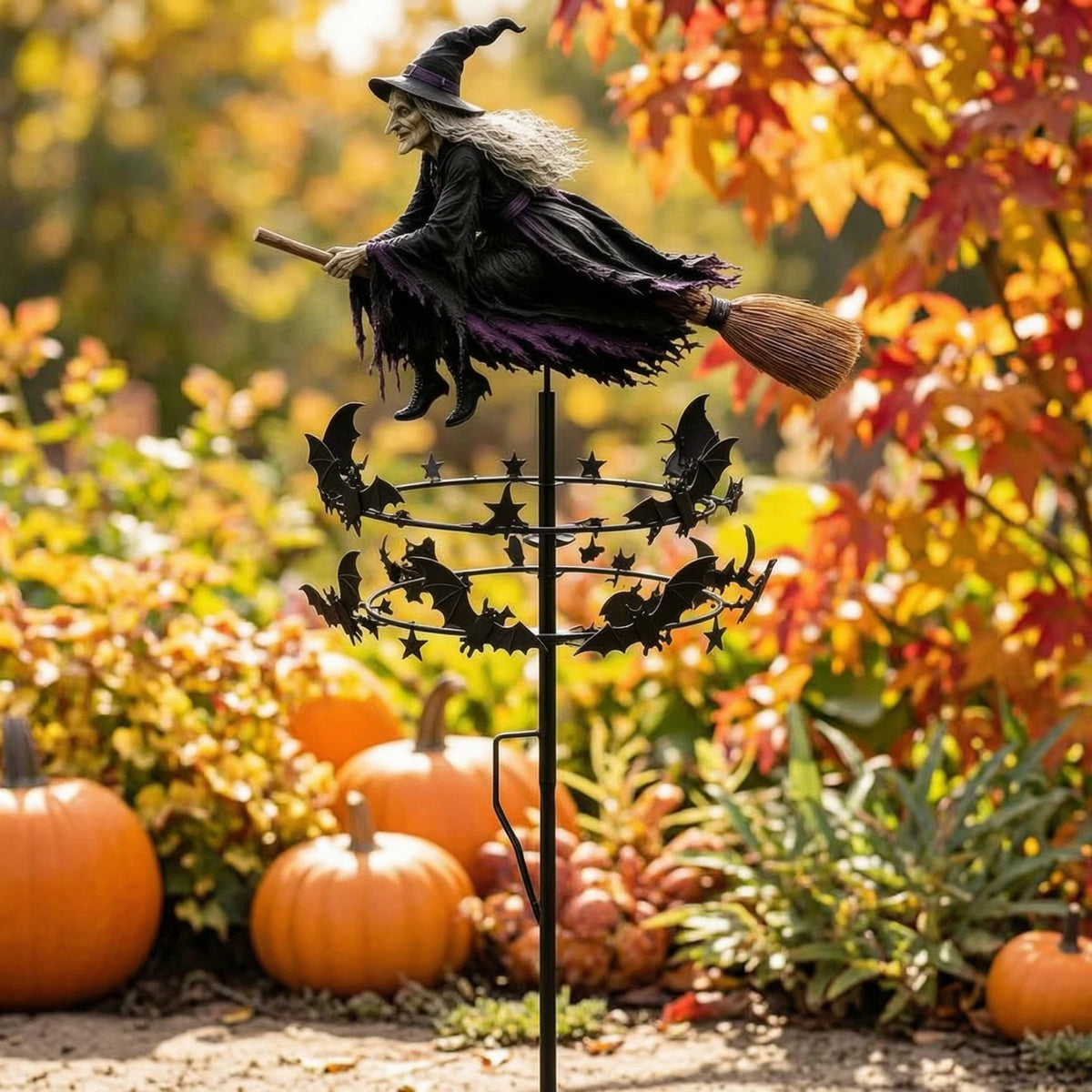 A whimsical witch wind rotor garden decor featuring a witch figure with a pointed hat and feathered wings, set against an aut
