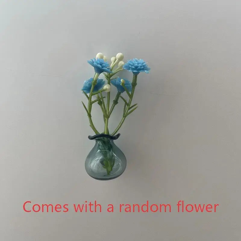 A small glass vase holds a cluster of blue and white flowers for fridge decor.