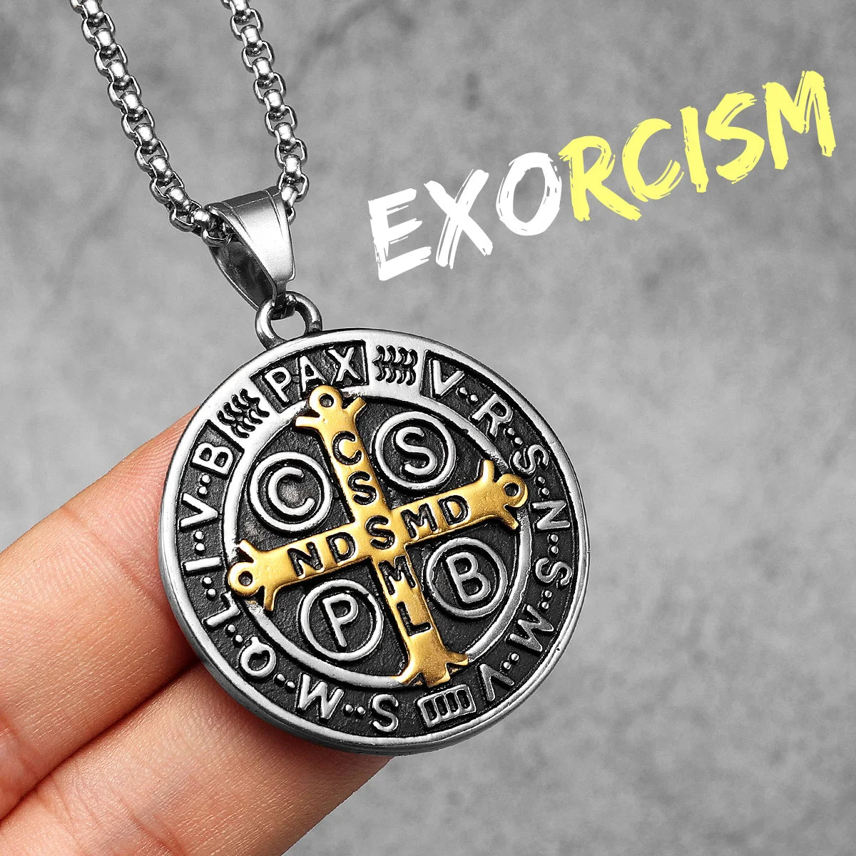A stainless steel punk cross necklace with Latin text and a pendant is held against a gray background.