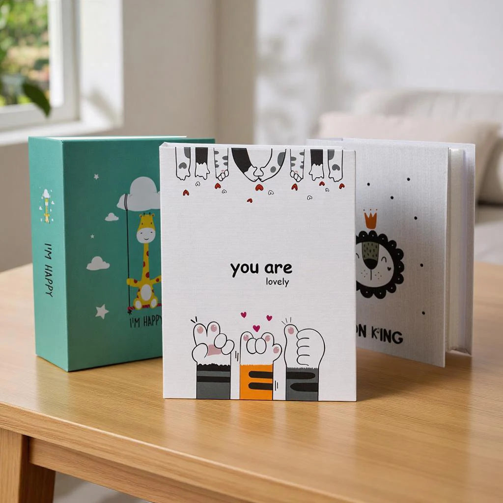 A set of three cartoon cover photo albums featuring cute animal characters and text on a wooden table.