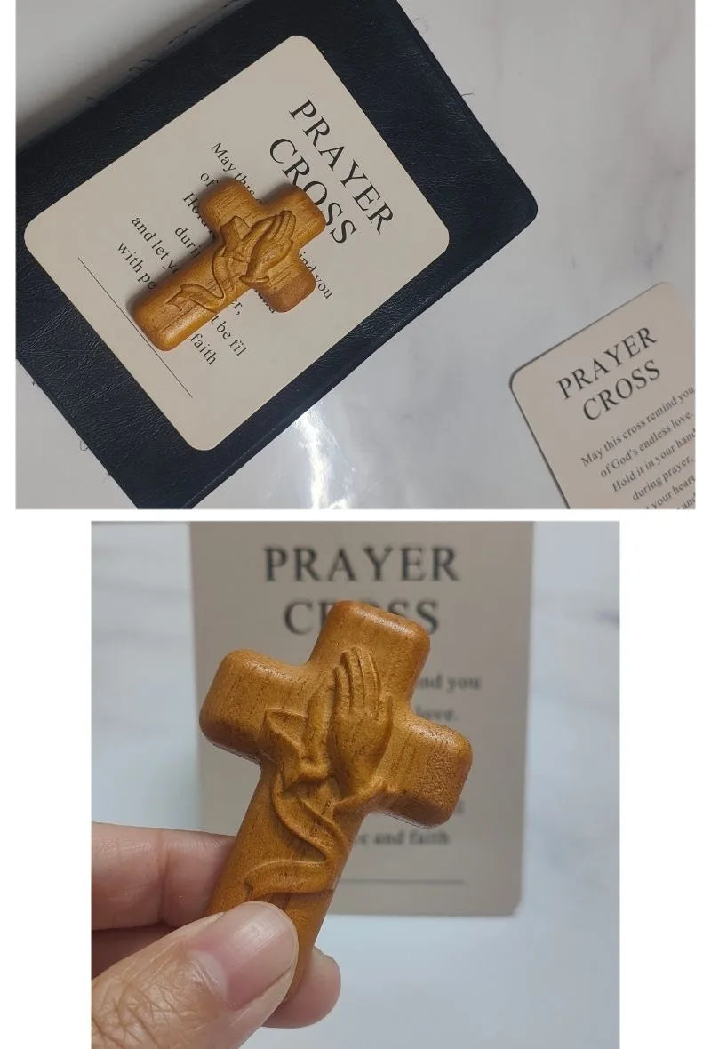 A handcrafted wooden prayer cross with a relief of a praying hand, displayed on a card.