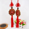 Red and gold mystic knot wall decor featuring tassels and circular designs