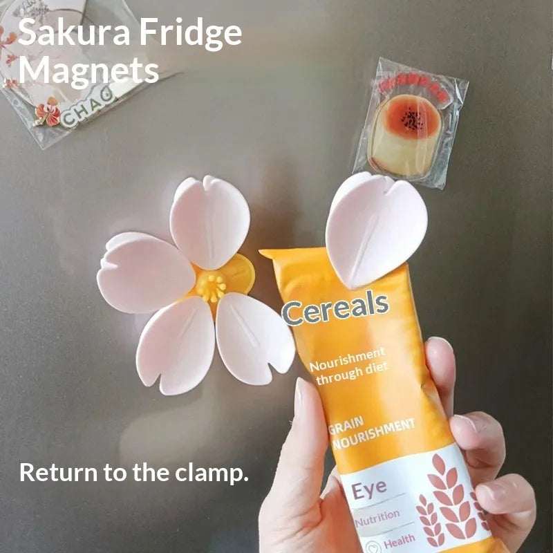 A hand holds a yellow tube of Cereals next to a pink flower magnet on a refrigerator.