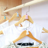 A set of three colorful hanger connector hooks are displayed on a wooden clothing hanger.