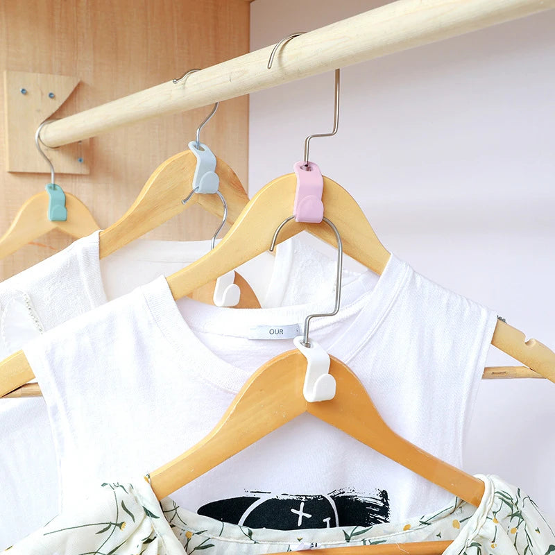 A set of three colorful hanger connector hooks are displayed on a wooden clothing hanger.