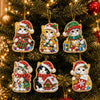 A set of Christmas diamond art ornaments featuring cats in Santa, snowman, and reindeer designs hanging on a green tree.