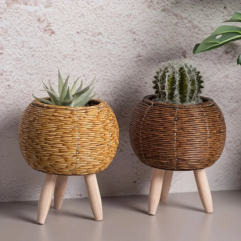 A rustic rattan planter with a cactus sits on wooden legs against a light background.