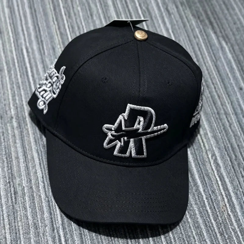Black baseball cap embroidered with a silver star design and a metallic pin.