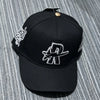 Black baseball cap embroidered with a silver star design and a metallic pin.