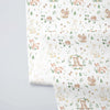A fabric print featuring a delicate floral pattern with woodland animals like rabbits, squirrels, and deer on a light backgro