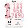 A set of seven pink foil balloons shaped like numbers 1 through 0 with black bows.