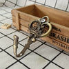 A pair of vintage gold-toned crown curtain hooks resting inside a wooden box with engraved text.