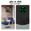 A glow-in-the-dark wooden wall clock showing 12 o'clock and a night display.