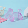 A translucent pink squishy toy shaped like a dachshund lying down on a light blue surface.