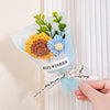 A bouquet of handmade crochet flowers in yellow and blue velvet blooms wrapped in clear cellophane with a best wishes tag