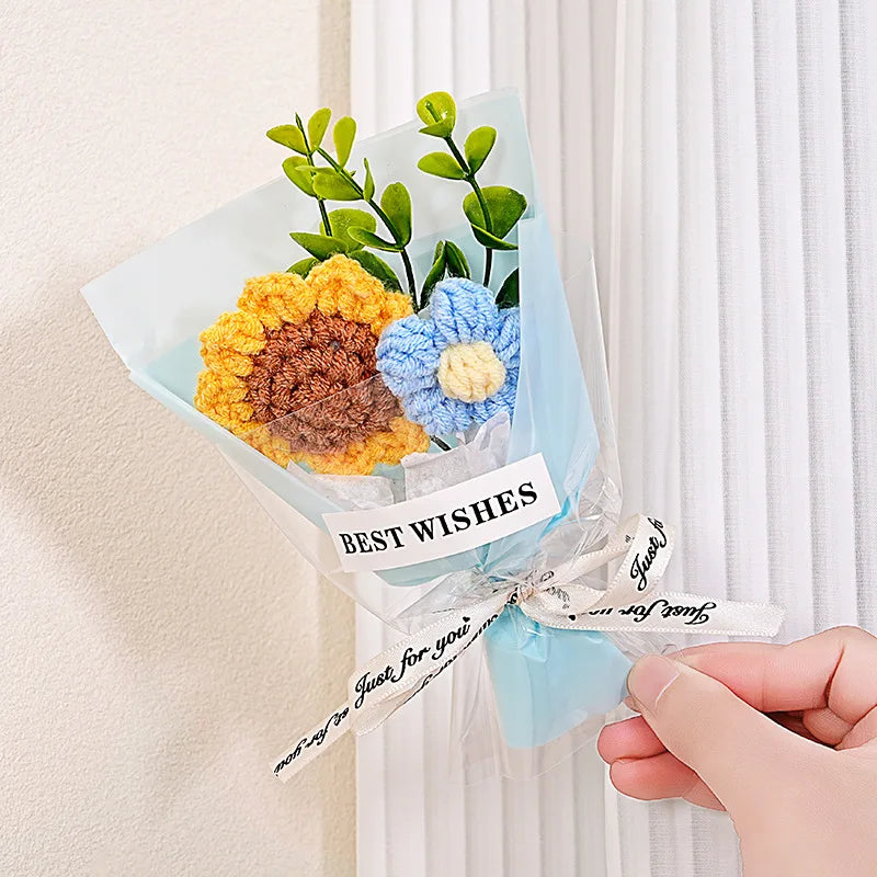 A bouquet of handmade crochet flowers in yellow and blue velvet blooms wrapped in clear cellophane with a best wishes tag