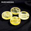 Five smooth, translucent yellow citrine crystals displayed on a black fabric.