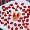 A collection of 50 red and black ladybug resin nail art charms displayed on a white surface.