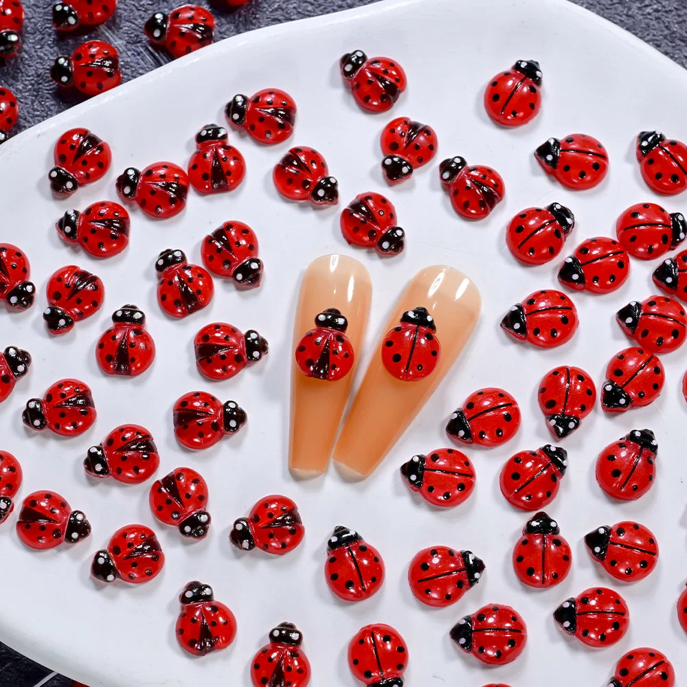 A collection of 50 red and black ladybug resin nail art charms displayed on a white surface.