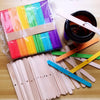 A collection of colorful wooden candle wicks and a glass jar are displayed on a wooden surface.