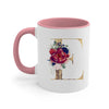 A pink ceramic coffee mug featuring a large gold letter E decorated with floral elements.