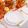 A set of gold rim plastic plates is displayed on a white tablecloth with autumn-themed decor.